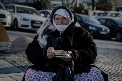 Woman sitting on street in city during winter