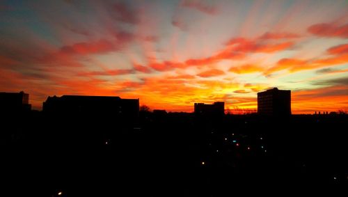 Silhouette of buildings against cloudy sky at sunset