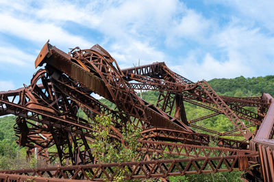 Old rusty metallic structure on field against sky