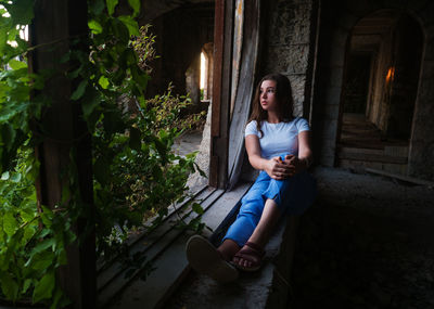 Teen girl sitting by the window in an abandoned building