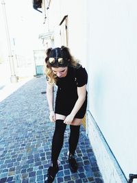 Full length portrait of young woman standing against wall
