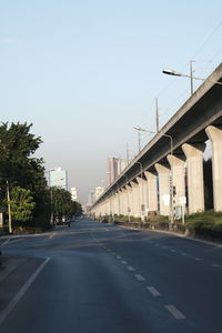 Road leading towards city against clear sky