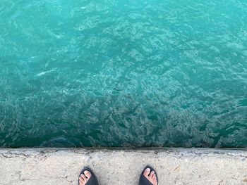 Low section of person standing by swimming pool