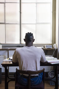 Rear view of man standing by window