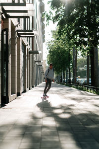 Young casual man on longboard riding to work or study down city street. youth lifestyle concept