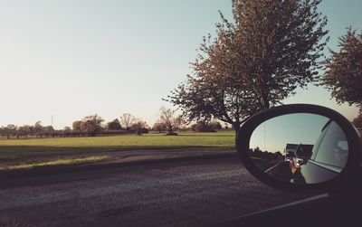 Close-up of side-view mirror against clear sky