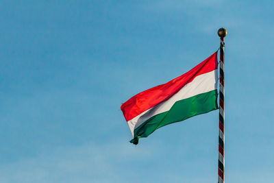 Low angle view of flag against blue sky