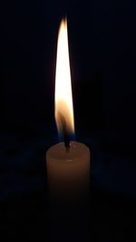 Close-up of lit candle in the dark