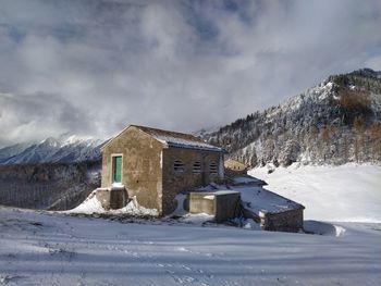 Buildings on snowcapped mountain against sky