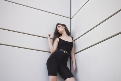 Young slim woman in leggings and black top in a fashionable pose