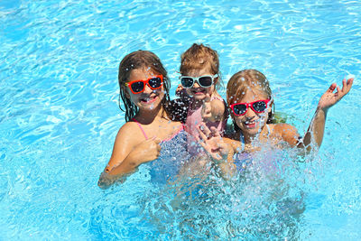 High angle view of siblings enjoying in swimming pool