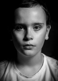 Close-up portrait of beautiful young woman against black background