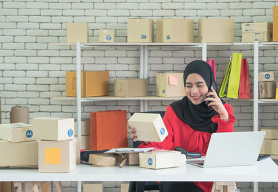 Young woman using phone while standing on table