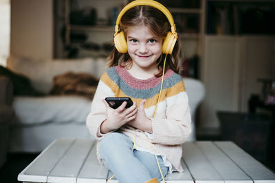 Portrait of smiling girl holding smart phone at home