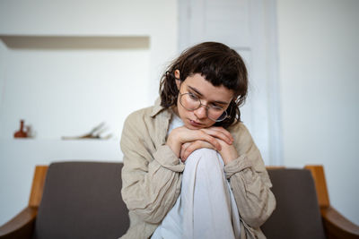 Young woman sitting on sofa at home