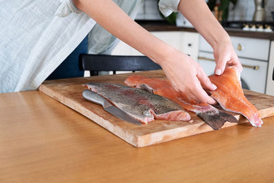 Female hands cutting fillet of red fish. red caviar. removing fish bones. butchering red fish meat.