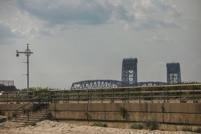 View of bridge and buildings against cloudy sky