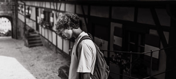 Side view of young man standing against building