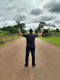 Rear view of man standing on road against trees