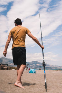 Rear view of man on beach against sky