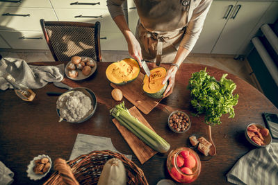 Young woman cleans pumpkin with knife for baking in apron in kitchen. the concept of healthy eating