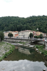 Bridge over river by buildings against sky