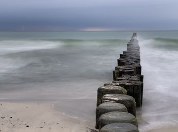 Wooden posts on beach against sky