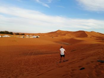Rear view of man playing on desert against sky