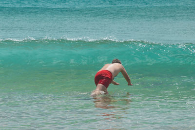 Rear view of shirtless boy swimming in sea