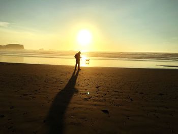 Silhouette people on beach against sky during sunset