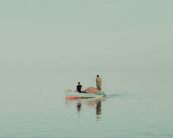 People on boat in sea against sky