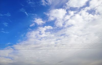 Low angle view of power cables against sky