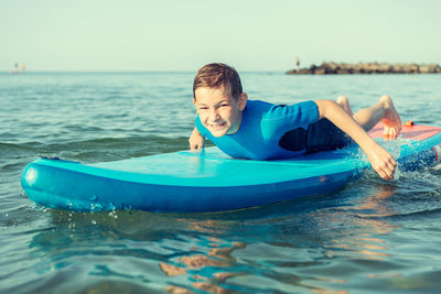 Boy in sea against sky