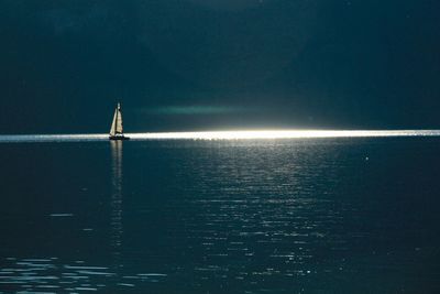 Sailboat in sea against sky at night