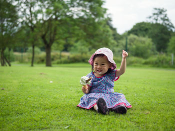 Happy baby girl eating ice cream while sitting on grassy field at park