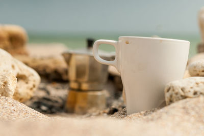 Close-up of coffee cup on beach