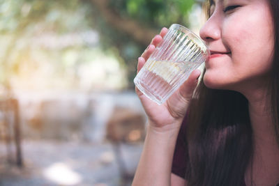 Close-up of woman drinking water from glass