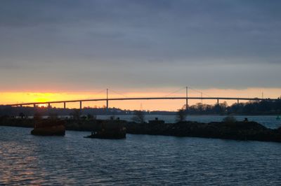 Bridge over sea against sky during sunset