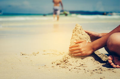 Cropped image of person making sandcastle at beach