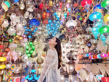 Woman standing against multi colored lights