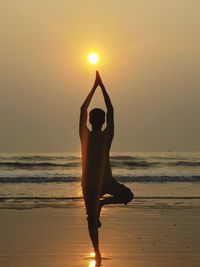 Man standing on beach against sky during sunset