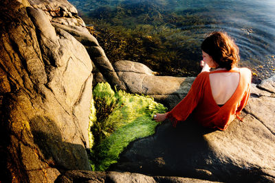 Rear view of woman sitting on rock