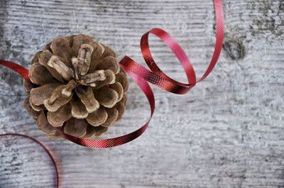 Directly above shot of pine cone with red ribbon on table