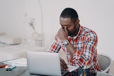 Side view of young man using laptop at home