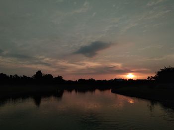 Scenic view of lake against cloudy sky during sunset