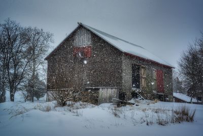 Built structure on snow covered field by building against sky