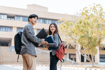 Friends looking while standing in campus