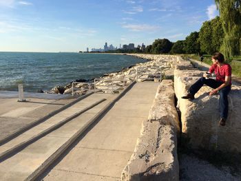 Rear view of man walking on footpath by sea