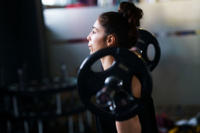 Side view of woman exercising with barbell in gym