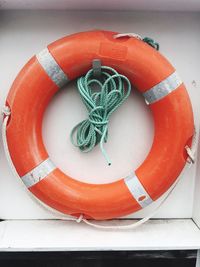 Orange life belt and rope against white wall